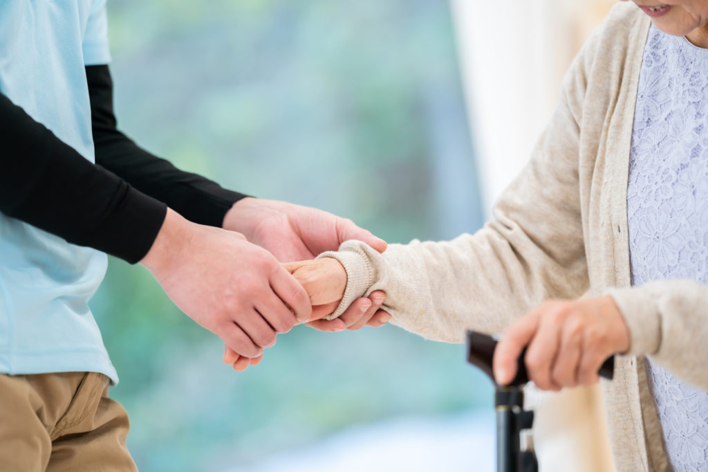 介護崩壊　日本-老人に手を添える介護スタッフ